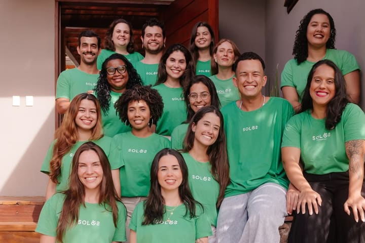 A equipe da Solos, de camiseta verde, reunida em frente a um galpão.