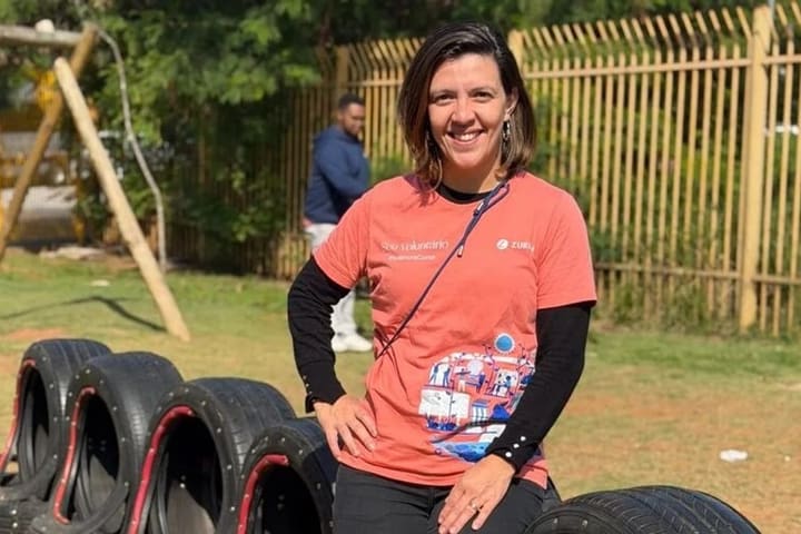 Integrante do Zurich Recicla sentada sobre pneus reaproveitados num parquinho.